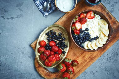 kase çilek, muz ve ekşi krema, taze meyveler ve yazlık Kahvaltı, yatay süzme peynir. karanlık beton zemin üzerinde üstten görünüm bir yemekler yiyecek ile. wintage bakır plaka üzerinde taze çilek