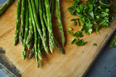kuşkonmaz, maydanoz ve fesleğen ile kesme tahtası