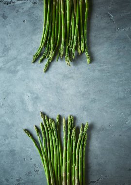 gri beton arka plan üzerinde taze ham bahçe kuşkonmaz iki demet. Yemek pişirmek için malzemeler. Yemek geçmişi. Kopyalama alanı ile üstte görünüm.