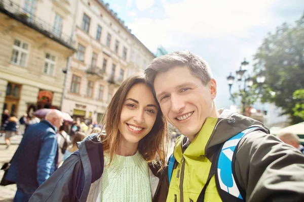 Счастливая молодая пара туристов прогуливаясь по центру города и делает селфи — стоковое фото
