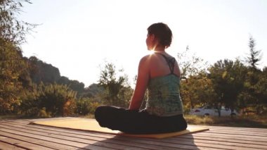 Genç bir kadın şafak tanışır ve bir ahşap bungalov verandada Yoga yapar