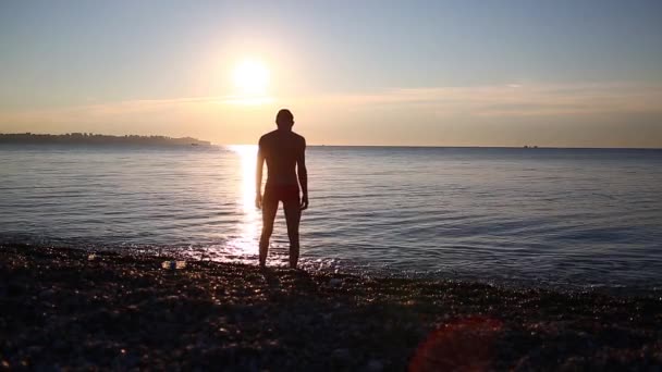 Человек на морском пляже на восходе солнца — стоковое видео