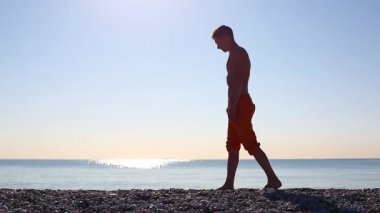 Genç bir adam şafak tanışır ve deniz sahilde Yoga yapar