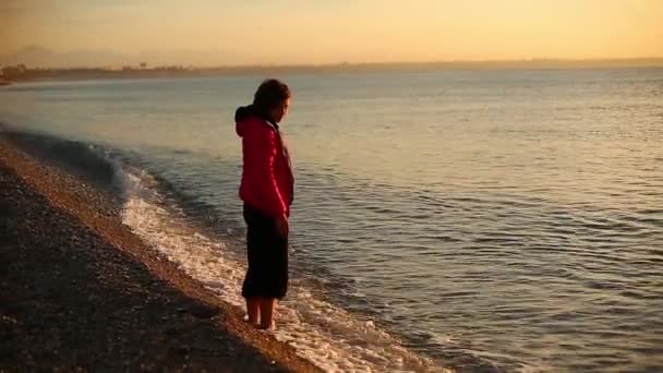 Jonge vrouw aan het strand van de zee bij zonsopgang — Stockvideo