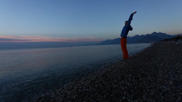Man op het strand van de zee bij zonsopgang — Stockvideo