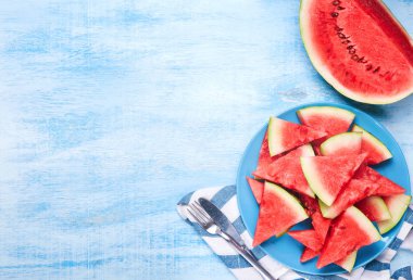 Karpuz dilimleri mavi ahşap masa mavi plaka üzerinde. Üstten görünüm, düz yatıyordu. Yaz aylarında konsept