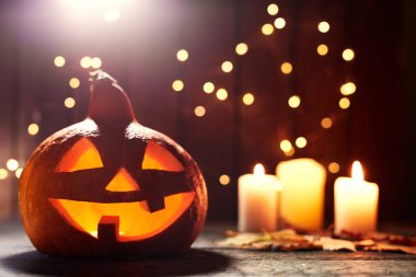 Cadılar Bayramı ve parlak zemin üzerine mumlar sembolü olarak korkunç yüzü ile oyulmuş kabak. Cadılar Bayramı dekorasyon konsepti