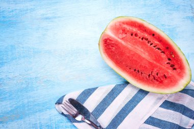 Karpuz ve çizgili peçete mavi ahşap masanın üstüne kesmek. Üstten görünüm, düz yatıyordu. Yaz aylarında konsept