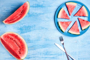 Karpuz dilimleri mavi ahşap masa mavi plaka üzerinde. Üstten görünüm, düz yatıyordu. Yaz aylarında konsept