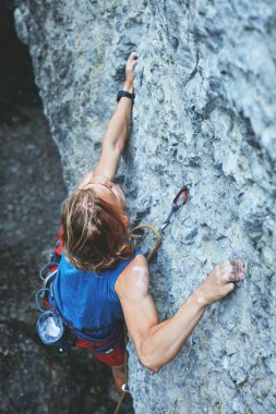 adam dağcı uzun saçlı. Genç adam kaya tırmanışçısı zorlu yol cliff üzerinde tırmanma parlak kırmızı şort üstten görünüm. kaya tırmanışçısı kayalık bir duvara tırmanıyor. adam sert hareketi yapma