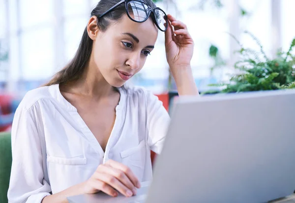 Fokusert, ung, vakker forretningskvinne som jobber på en bærbar datamaskin i et lysende, moderne kontor – stockfoto