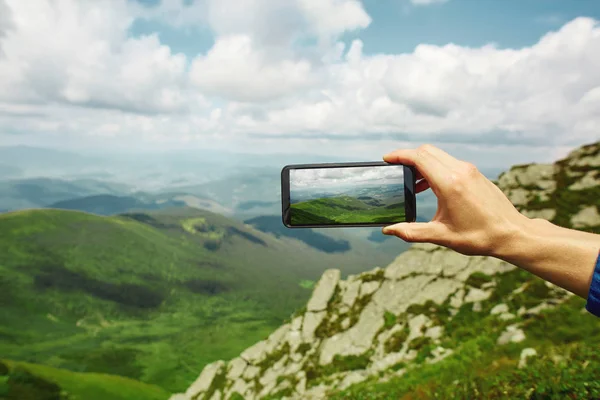 man photographing mountain landscape by the phone