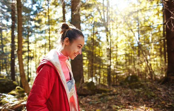 Feliz mujer sonriente en una chaqueta roja camina en el bosque de otoño — Foto de Stock