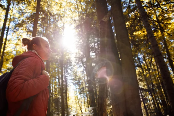 Feliz mujer sonriente en una chaqueta roja camina en el bosque de otoño — Foto de Stock