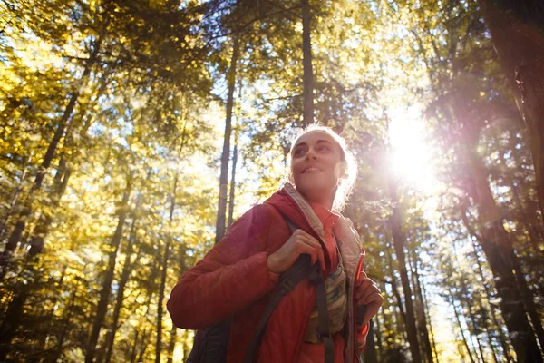 Heureuse femme souriante dans une veste rouge marche dans la forêt d'automne — Photo