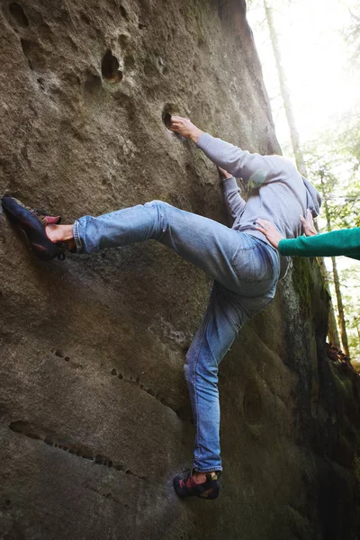 A man rock climber climbing a rock and his partner insuring. — Stock Photo, Image