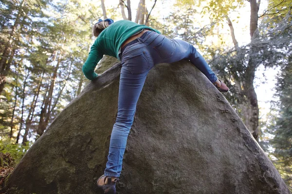 Una mujer escaladora escalando una roca al aire libre en el bosque — Foto de Stock