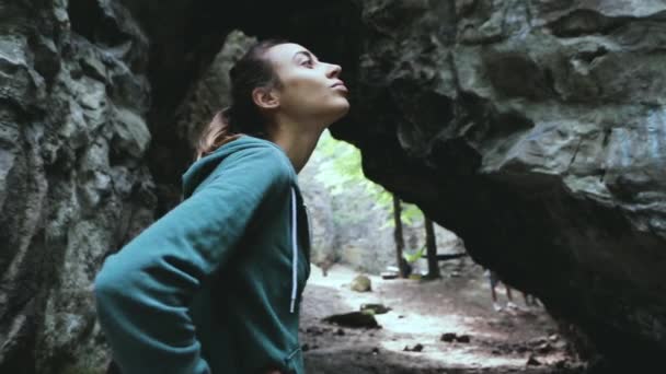 一位女游客高兴地看着森林里的岩石 — 图库视频影像
