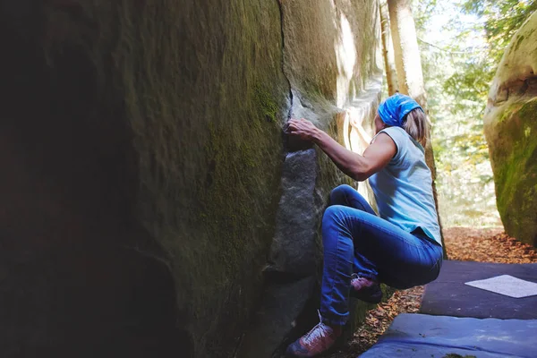 Una donna scalatrice di roccia che scala una roccia all'aperto nella foresta — Foto Stock