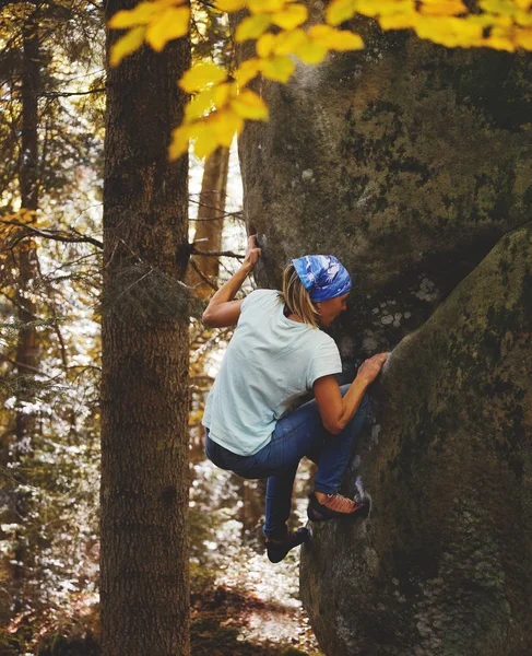 Una donna scalatrice di roccia che scala una roccia all'aperto nella foresta — Foto Stock