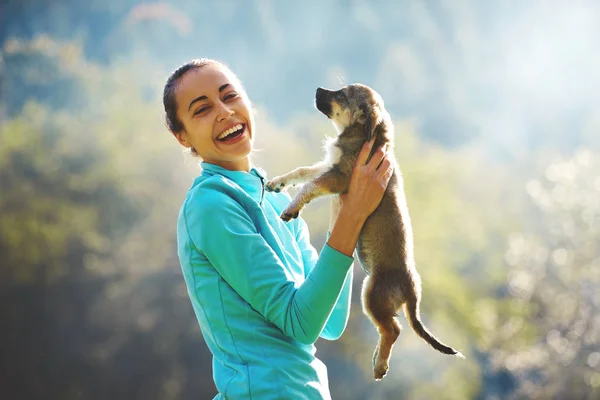 Wanita muda bermain dengan anak anjing kecil yang lucu di rumput hijau di perkemahan — Stok Foto