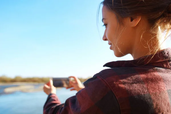 Mujer en camisa hipster rojo está fotografiando el río de montaña — Foto de Stock