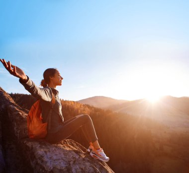 kadın gündoğumu çerçevede uçurumun kenarında oturur