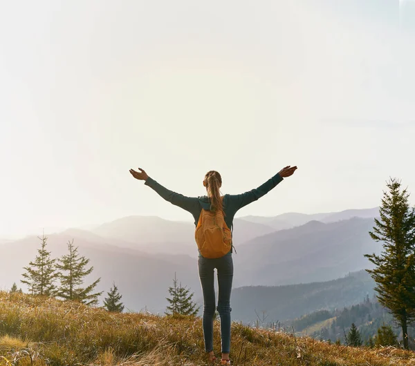 Mujer excursionista de pie en el borde de la cresta de la montaña sobre el fondo del atardecer —  Fotos de Stock