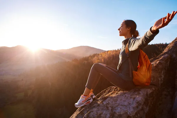 Femme assise sur le bord de la falaise sur fond de lever de soleil — Photo