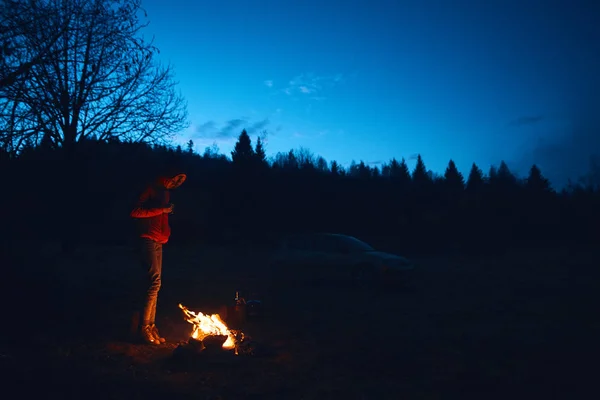 Jeune femme debout près du feu de camp — Photo