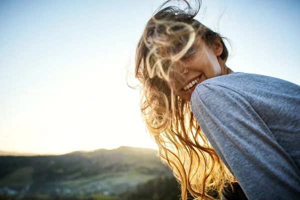 Woman sits on edge of cliff against background of sunrise — Stock Photo, Image