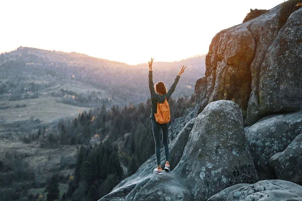 Mujer se levanta en el borde del acantilado contra el fondo de la salida del sol —  Fotos de Stock
