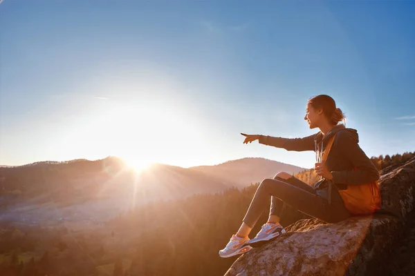 Vrouw zit op de rand van de klif tegen de achtergrond van zonsopgang — Stockfoto