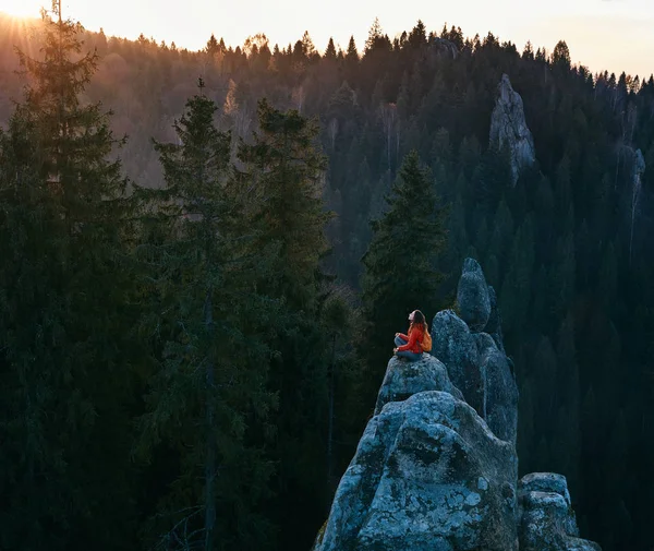Жінка стоїть на краю скелі на фоні лісу — стокове фото