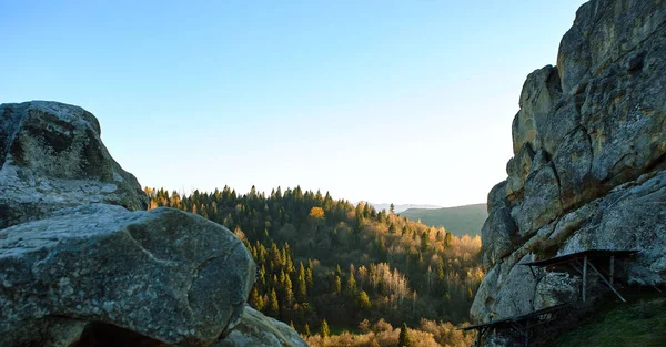 Soloppgang i nasjonalparken over skog og stein. Den stigende solen lyser vakkert opp toppen av furuene og fjellryggen. – stockfoto