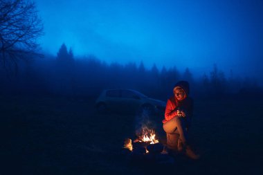 Kamp ateşi yanında oturan genç kadın
