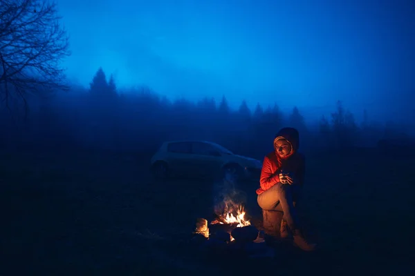 Ung kvinne sitter ved bålet – stockfoto