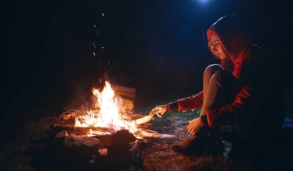 Young woman in sitting near the campfire Stock Picture