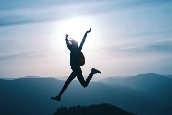 Mujer saltando en la montaña al atardecer cielo y montañas fondo —  Fotos de Stock