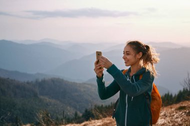 gün batımında dağ sırtı üzerinde duran ve fotoğraf çekme kadın uzun yürüyüşe çıkan kimse