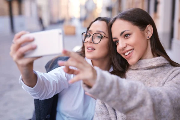 Dwie piękne kobiety, Dokonywanie selfie przez telefon w centralnej części miasta — Zdjęcie stockowe