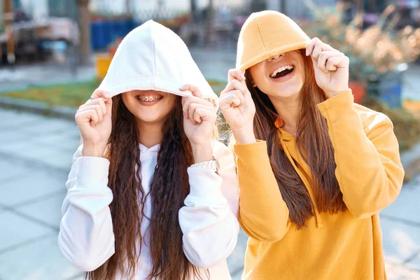 Twee jonge meisjes in hoodies lopen stad plezier — Stockfoto