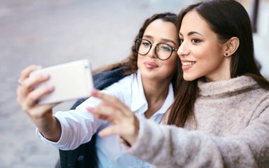 iki güzel kadın şehir orta kısmında telefonla selfie yapma