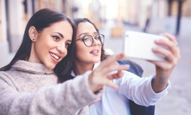 iki güzel kadın şehir orta kısmında telefonla selfie yapma