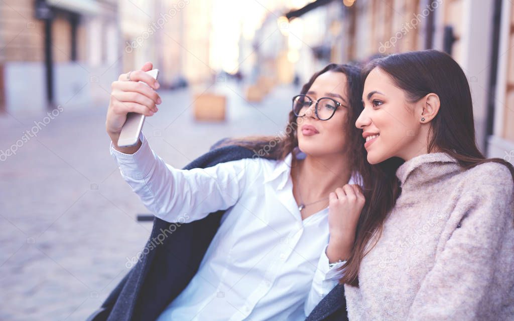 two beautiful women making selfie by the phone in the central part of city