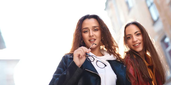 Twee jonge meisjes lopen stad plezier en kijkt neer op de camera — Stockfoto