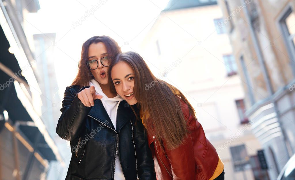 two young girls walking city having fun and looking down at the camera