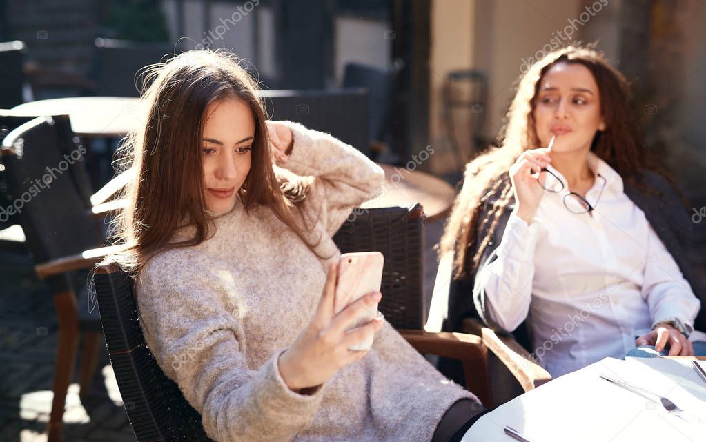 two beautiful women sitting in street cafe at sunny spring day