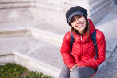 Genç kadın kırmızı ceket ve gri kap sokakta poz