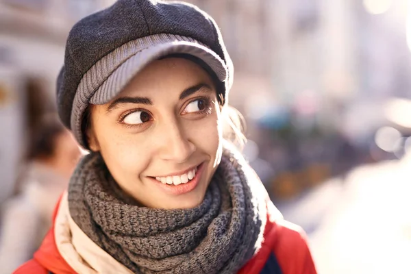 Mujer joven con chaqueta roja y gorra gris posando en la calle — Foto de Stock